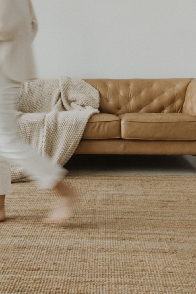 A woman quickly walking away from a couch.